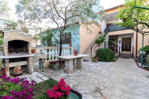 a patio with a stone fireplace in front of a house at Apartmenthaus Mira Eldic in Fažana