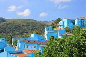 a group of blue houses on a hill with trees at Casa Rural Fuente Caraila in Júzcar