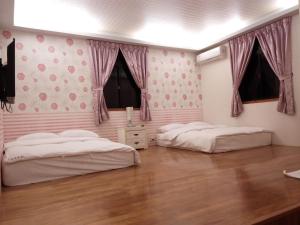 Duas camas num quarto com paredes cor-de-rosa e pisos em madeira em Tai Yu Ju Bao Fang B&B em Yung-an-ts'un