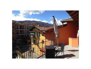 einen Balkon mit einem Stuhl und einem Regenschirm auf einem Gebäude in der Unterkunft Apartments La Lombarda Centro Storico Stresa in Stresa