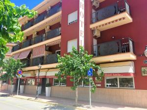 un edificio rojo con balcones en un lateral en Hotel Ancla, en Oropesa del Mar