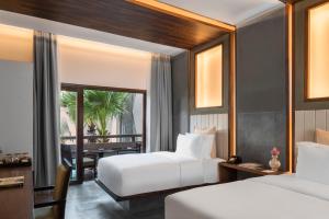 a hotel room with two beds and a dining area at Jaya House River Park in Siem Reap