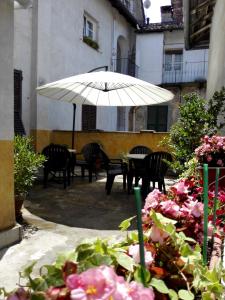 um pátio com uma mesa, cadeiras e um guarda-sol em ViaBasso11 Guest House em Novi Ligure