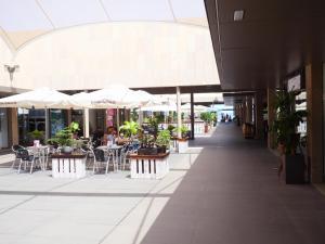an empty shopping mall with tables and chairs and umbrellas at Luxury Apartment Las Terrazas in El Médano