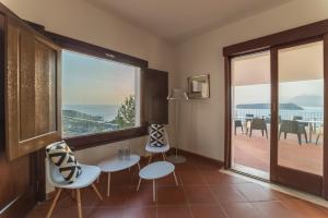 a room with a large window and a table and chairs at Villa Crawford in San Nicola Arcella