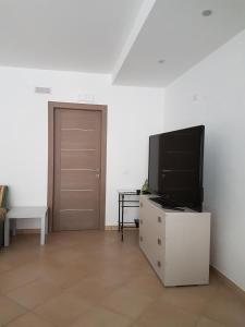 a living room with a television on a dresser with a door at Bed & Breakfast La Pilona in Bagnolo San Vito