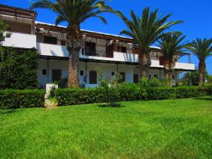 a building with palm trees in the yard at Meroi Studios in Skiros