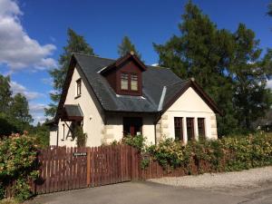 una pequeña casa blanca con una valla de madera en Dullatur en Newtonmore