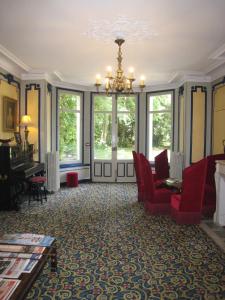 a living room with red chairs and a piano at Hôtel Les Maréchaux in Auxerre