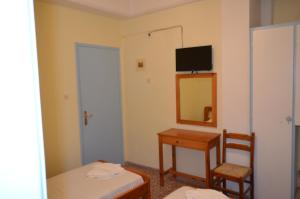 Zimmer mit einem Tisch, einem Spiegel und einem Bett in der Unterkunft Galaxy Hotel in Gavrio