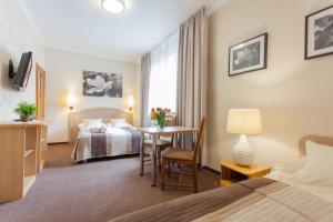 a hotel room with a bed and a desk and a table at Villa Anna - Noclegi Rooms - FREE parking, taras, 1500m do Starówki in Gdańsk