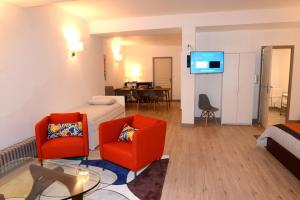 um quarto com duas cadeiras e uma cama e uma televisão em Les Chambres Panda em Saint-Aignan