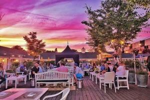 un grupo de personas sentadas en mesas con una puesta de sol en el fondo en Capri Southampton en Southampton