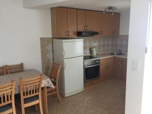 a kitchen with a white refrigerator and a table with chairs at Apartments Aldomar in Biograd na Moru