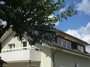 une maison blanche avec un balcon et un arbre dans l'établissement Hafners im Allgäu, à Kißlegg