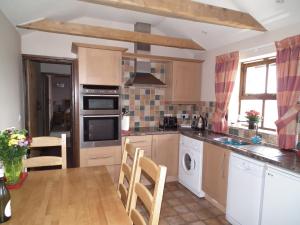 a kitchen with a table and a stove top oven at The Barn, Lower Spring in Tavistock