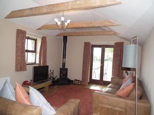 sala de estar con 2 sofás y TV en The Barn, Lower Spring, en Tavistock