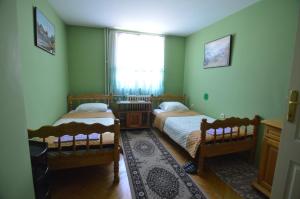 a bedroom with two beds and a window and a rug at Hotel 24 jul in Pljevlja