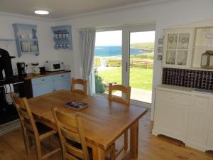 uma cozinha e sala de jantar com uma mesa e uma janela em Driftwood Cottage em Staffin