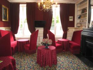 a living room with red chairs and a table with flowers at Hôtel Les Maréchaux in Auxerre