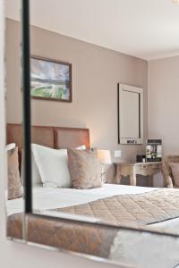 1 dormitorio con cama, escritorio y espejo en The Glen Guest House en Kendal