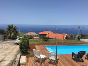 a house with a swimming pool with chairs and the ocean at Casa das Marias in Ponta do Pargo