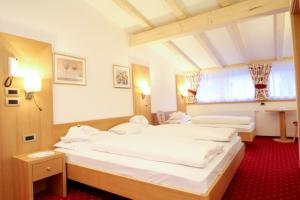 a room with three beds and a window at Garni Crepaz in Selva di Val Gardena