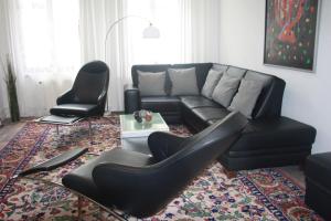 een woonkamer met een zwarte bank en 2 stoelen bij Ferienwohnungen Harz Wernigerode in Wernigerode