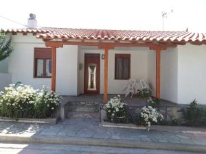 a small white house with a porch and flowers at Galina Holiday Home in Áyios Evstrátios