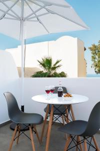 Mirto's Studios في فيرا: طاولة مع كأسين من النبيذ ومظلة