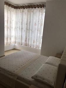 a bed in a bedroom with a window with curtains at Radhima Beach Apartment-Tirana Resort in Orikum