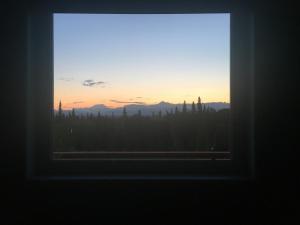 ein Fenster mit Blick auf den Sonnenuntergang in der Unterkunft Grace and Bill's Freedom Hills B&B in Talkeetna