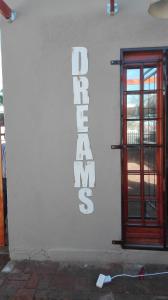 a white building with a door and a sign on it at Dreams in Beaufort West