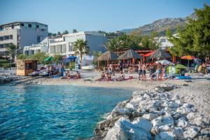 a beach with a group of people sitting on the sand at Apartments Casablanca in Podstrana