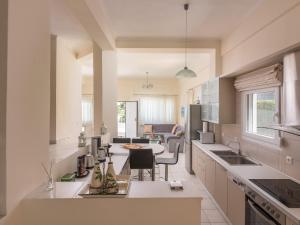 a kitchen with white cabinets and a table in it at Aegean Residence - F & B Summer Collection in Kallithea Halkidikis