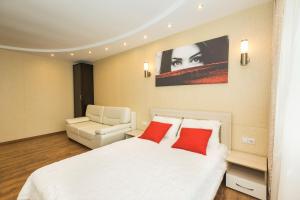 1 dormitorio con cama blanca y almohadas rojas en 5days-nn, Studio apartment on Yarmarochnyy Proyezd, 8, en Nizhny Novgorod