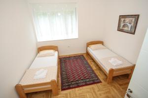 - 2 lits dans une chambre avec une fenêtre et un tapis dans l'établissement Apartment Alsa, à Mostar
