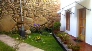 a garden in front of a stone wall at Quinua Boutique Apartments in Cusco