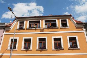 un bâtiment orange avec des fenêtres et des boîtes de fleurs dans l'établissement Apartments & Suites Žlutá Hruška, à Plzeň