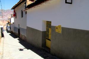 a white building with a yellow door next to a sidewalk at Historical Center Apartments in Cusco