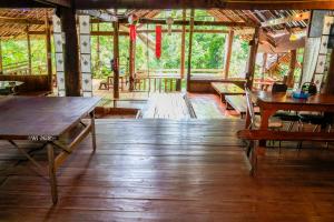 a room with wooden floors and tables and windows at Cave Lodge in Pang Mapha