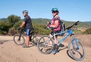 two people standing with their bikes on a dirt road at Villaggio Camping Calapineta in Siniscola