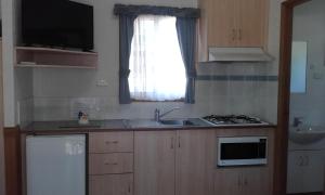 a kitchen with a sink and a stove and a window at Acclaim Gateway Tourist Park in Norseman