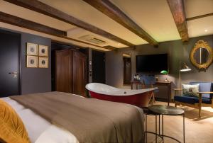 ein Schlafzimmer mit einem Bett, einem Stuhl und einem TV in der Unterkunft The Hendrick's Hotel in Amsterdam
