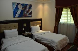 リヤドにあるManazilna Apartments Riyadhのベッド2台と窓が備わるホテルルームです。