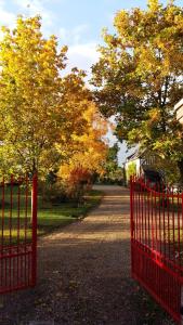 a red fence in front of a road with trees at Chambre d'hôtes - Le jardin des Patissons in La Foret Du Parc