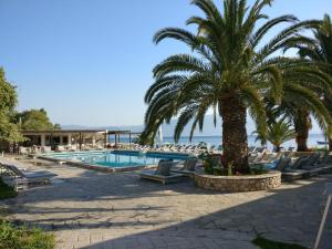 a pool with chairs and a palm tree and the ocean at Long Beach Hotel & Resort in Lóngos