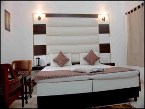 a bedroom with a bed with a large headboard at Hotel Sidhartha in Agra