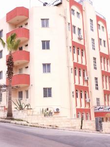 un grand bâtiment blanc avec un palmier devant lui dans l'établissement Sami Apartments, à Amman