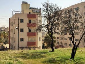 a tall building with a tree in front of it at Sami Apartments in Amman